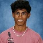 Young man with glasses, pink shirt, and necklace.