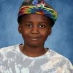 Boy in tie-dye hat and shirt, blue background.