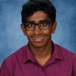 Smiling teen with glasses and braces, purple shirt.